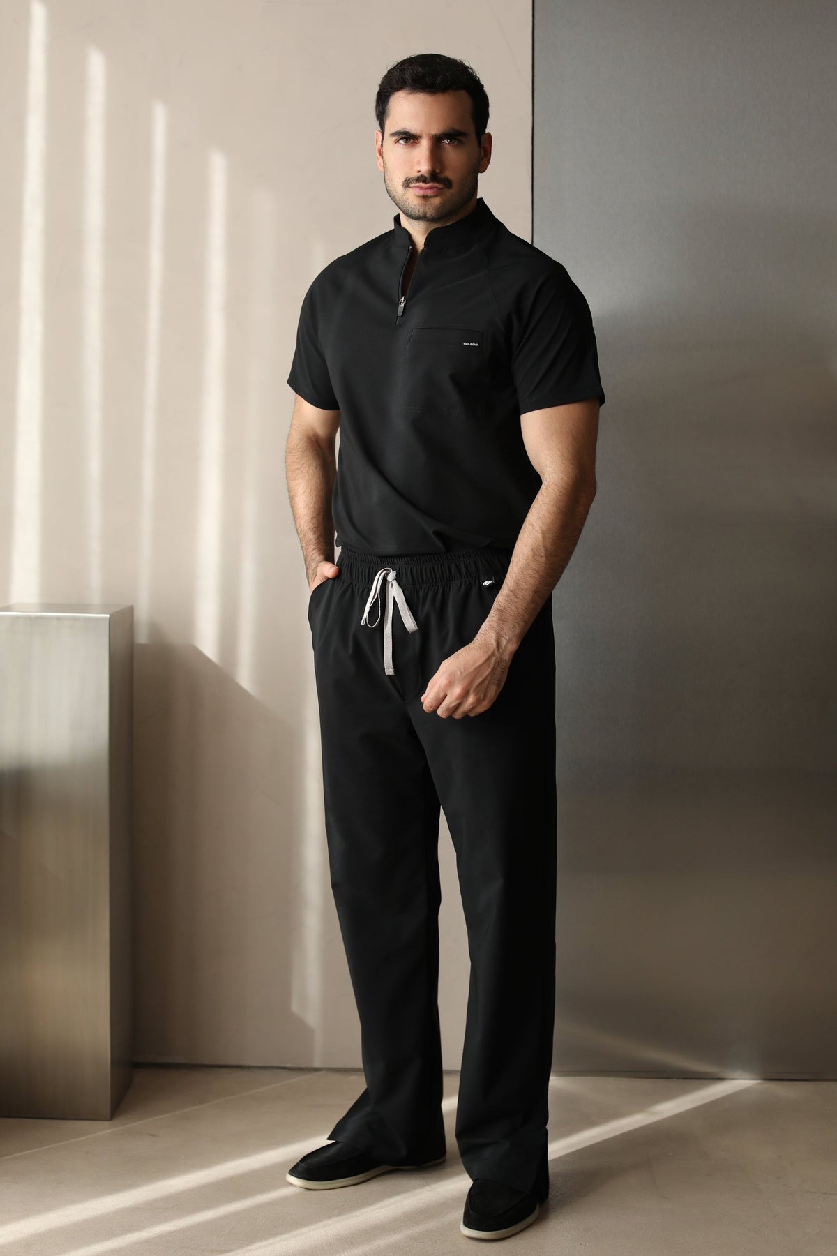 Full-body front view of a man wearing Harry Black W&C Shield™ scrub pants with the matching Harry Black scrub top.