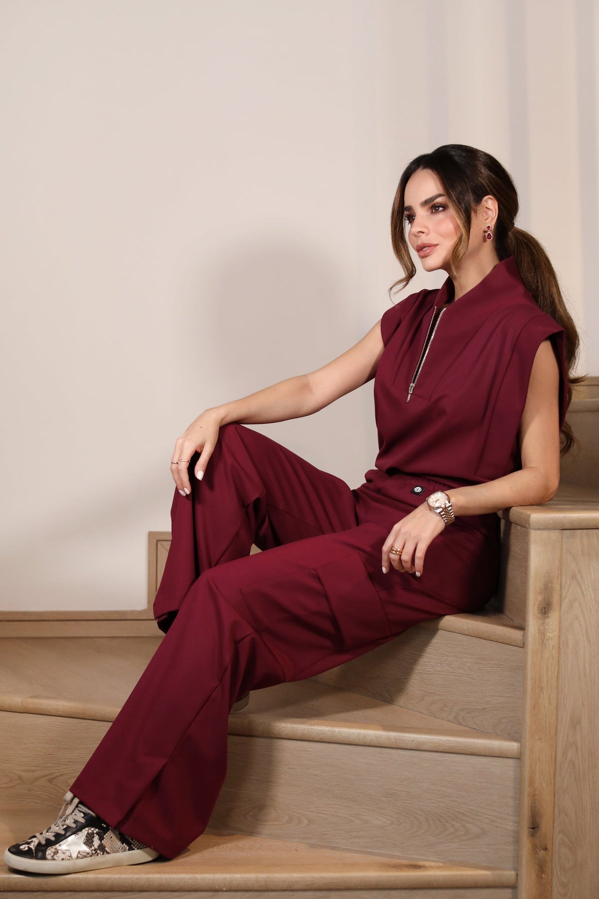 Model seated wearing Kate Burgundy Scrub Pants with the matching scrub top