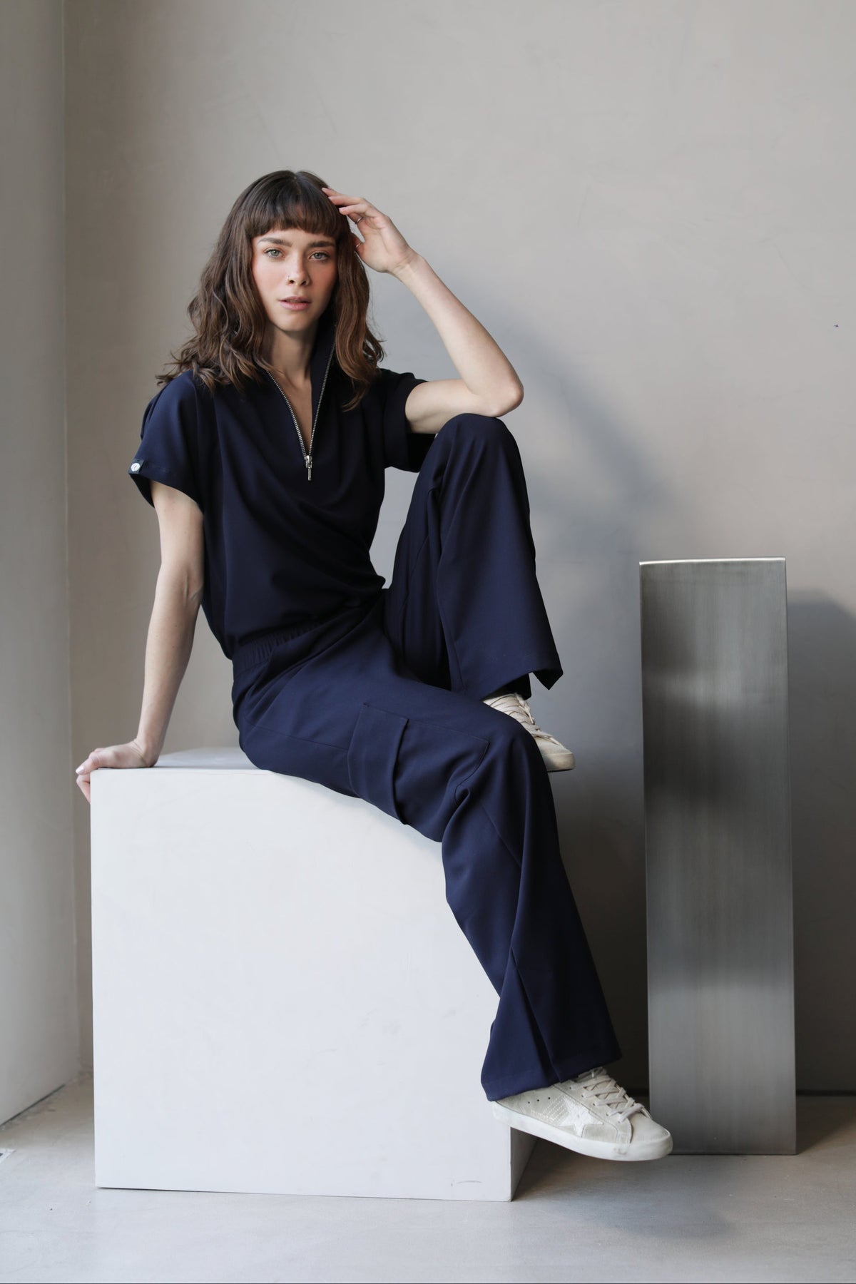 Model seated wearing Victory Navy Scrub Top with matching scrub pants
