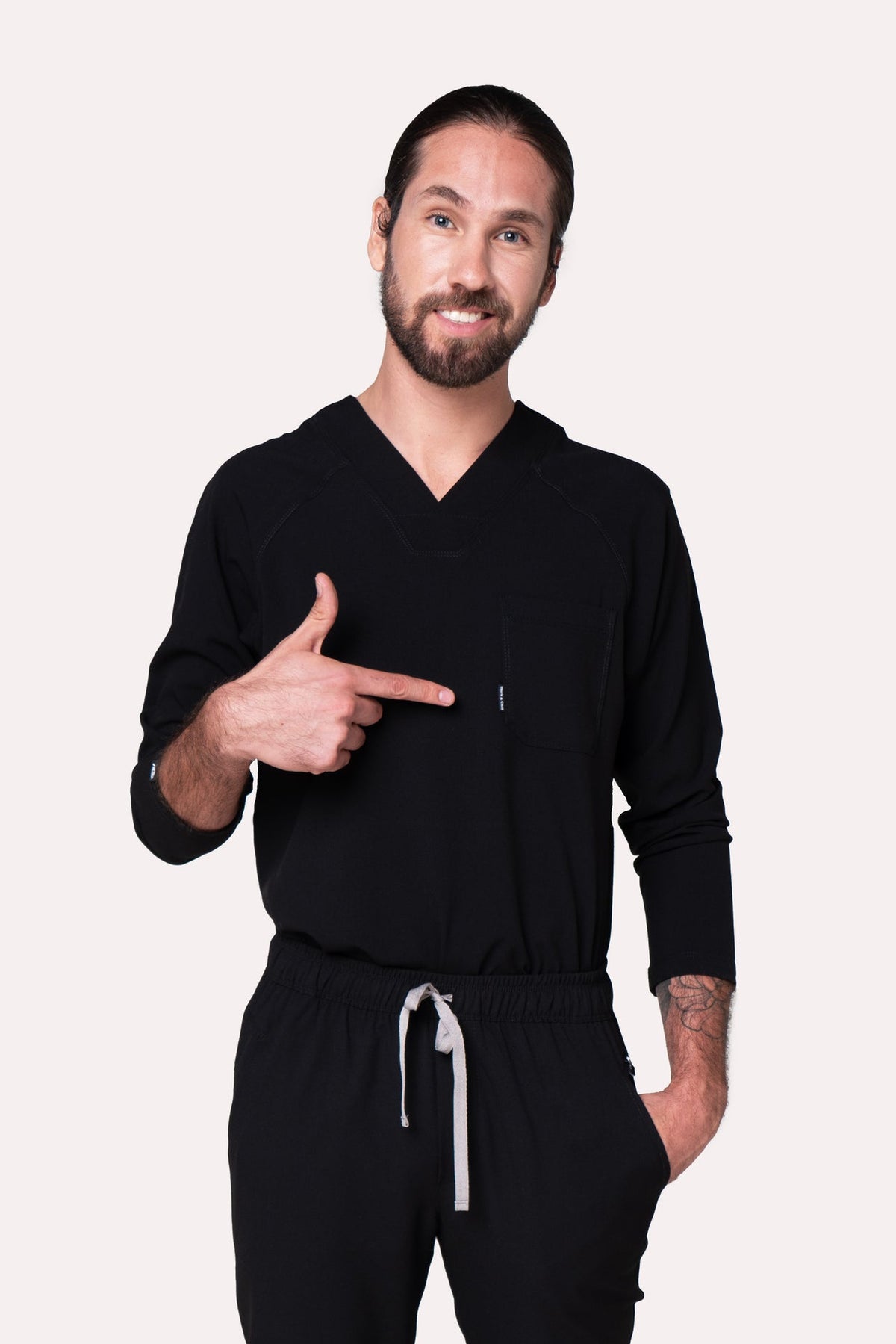Man wearing Classic Black Scrub Top showing the long sleeves and professional fit