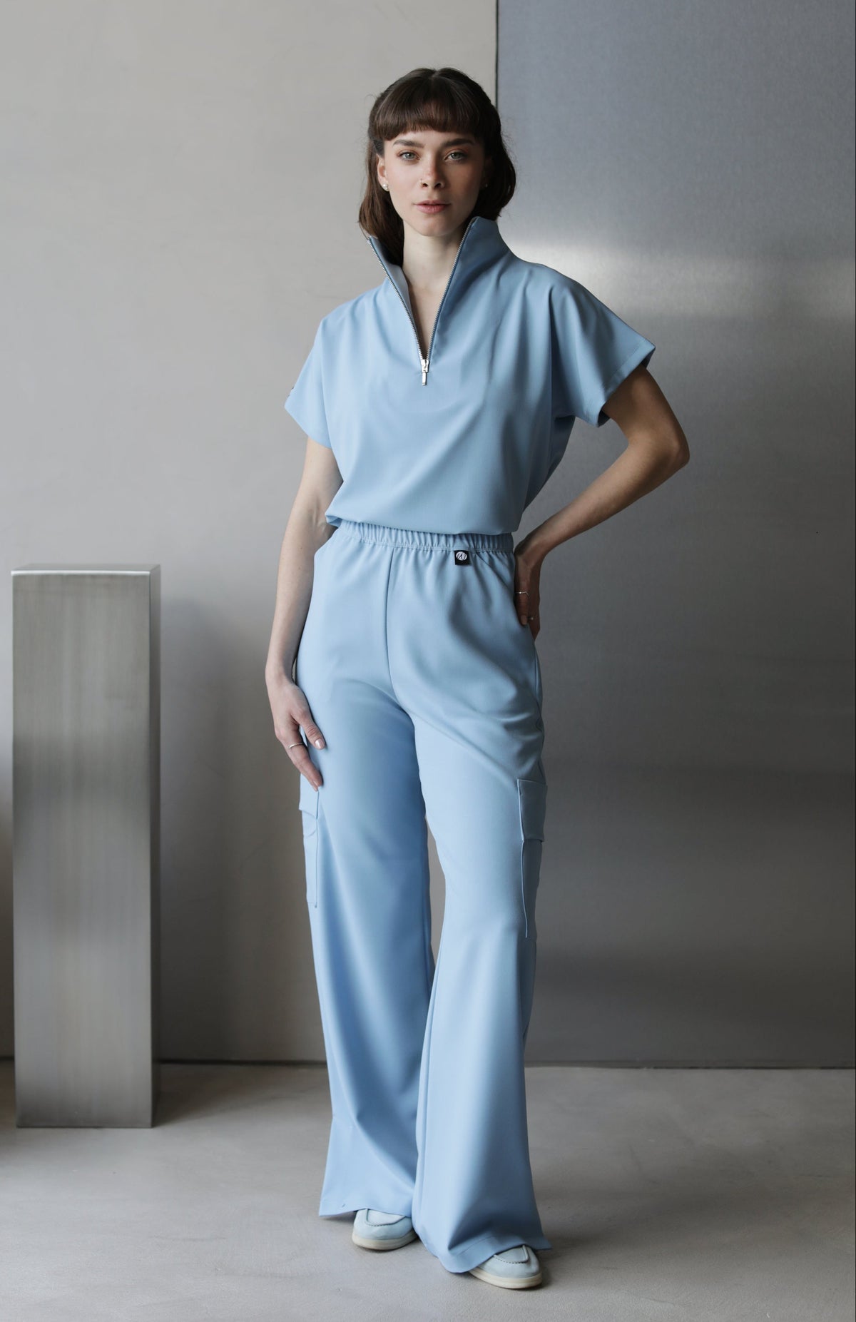 Model wearing Victory Dream Blue Scrub Top with matching scrub pants