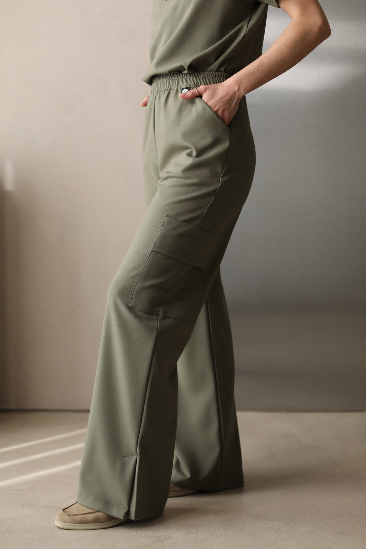 Side view of Victory Olive Scrub Top styled with matching scrub pants